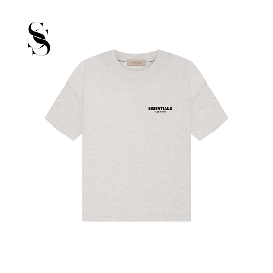 Camiseta de manga corta Fear of God Essentials en color gris jaspeado claro con logotipo frontal negro en el pecho sobre fondo blanco.