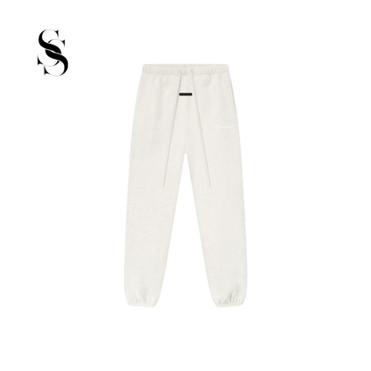 Pantalón tipo jogger Fear of God Essentials en color blanco hueso light oatmeal con cordones ajustables largos, parche frontal de goma y puños elásticos en los tobillos